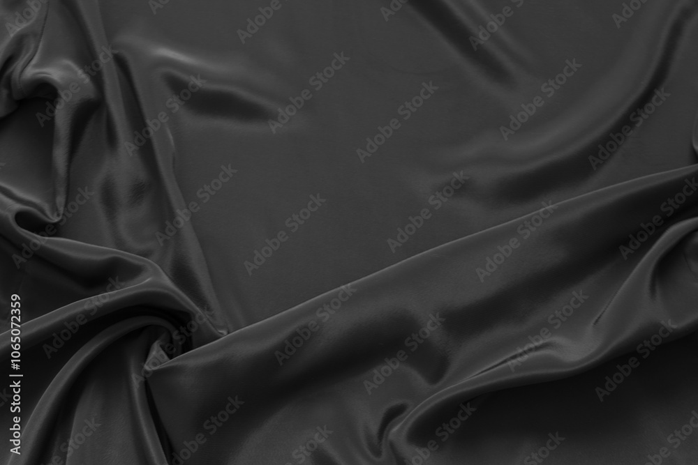Fototapeta premium Textile background of black fabric with soft folds in lower left corner and empty space for text on top. Beautiful backdrop for design or decoration. Mock up, flat lay, copy space, top view, blank