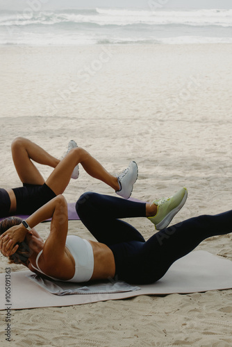 Two women practicing on mats on oceanfront. Outdoor exercise