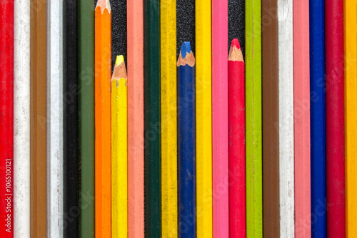 group of colored pencils in a row, on a black table