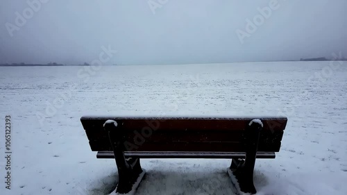 Solitary Park Bench in Open Snowy Field, Winter Snowfall on Isolated Park Bench
