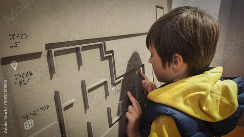 A boy reading the evacuation plan on the wall in braille. Close-up of a child reading braille. The concept of inclusiveness. World Sight Day. World Braille Day