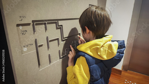 A boy reading the evacuation plan on the wall in braille. Close-up of a child reading braille. The concept of inclusiveness. World Sight Day. World Braille Day