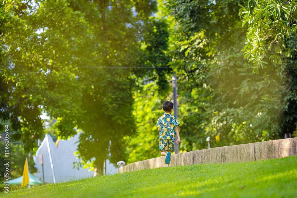 Obraz premium Asian boy enjoy run on green meadow grass city tree park