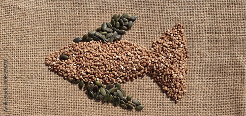 Healthy food, diet. Healthy buckwheat, pumpkin seeds and celery. Drawing of fish from products. Art healthy food. Fish drawing. Composition of useful products.