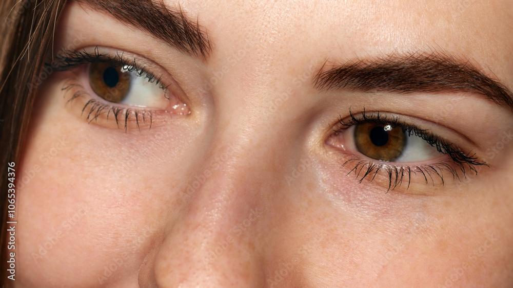 Close-up photo of young woman with bright brown eyes, long lashes and smooth facial skin against white background. Concept of beauty, healthcare, freshness and wellness, confidence. Ad Close-up photo of young woman with bright brown eyes, long lashes and smooth facial skin against white background. Concept of beauty, healthcare, freshness and wellness, confidence. Ad