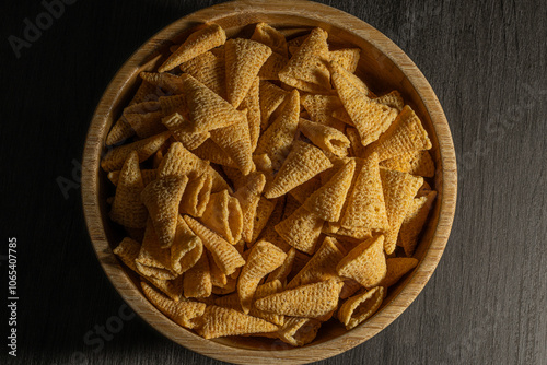  Un bol de madera lleno de conos de maíz crujientes, capturados en primer plano para resaltar su textura dorada y su irresistible apariencia. Un snack perfecto para disfrutar en cualquier momento. photo