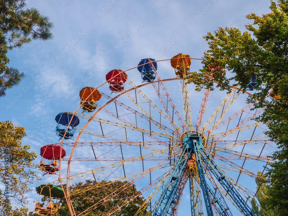 Colorful panoramic observation wheel of Soviet era on a sunny autumn day in an urban city Peremohy park in Kyiv, Ukraine.