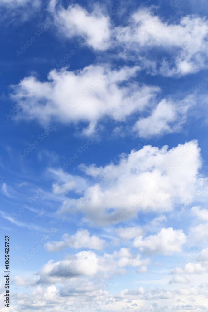 Fototapeta premium Blue cloudy sky with many beautiful white fluffy cumulus light clouds in sunlight background texture
