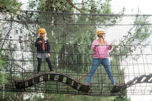 Adventure Park Kids Rope Bridge Two kids wearing hard hats stand on a rope bridge in an adventure park. photo