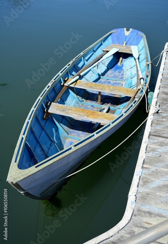 Pastel Blue faded painted rowing boat with oars moored on a wooden pier. photo