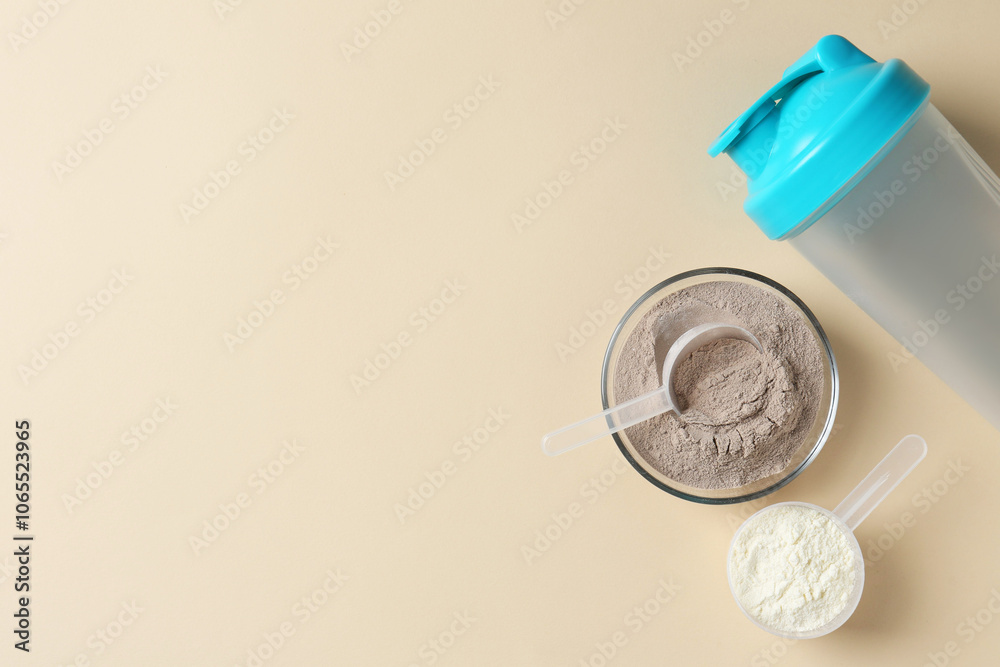 Protein powder in bowl, scoops and shaker on beige background, flat lay. Space for text Protein powder in bowl, scoops and shaker on beige background, flat lay. Space for text
