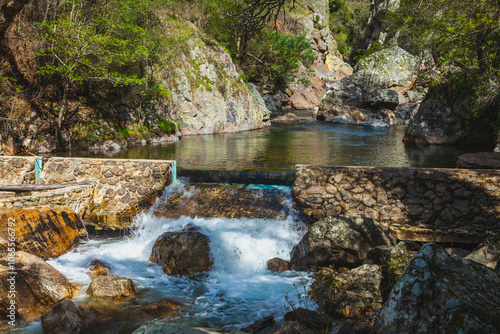 small waterfall cascading over a stone dam, nestled in a lush natural setting
