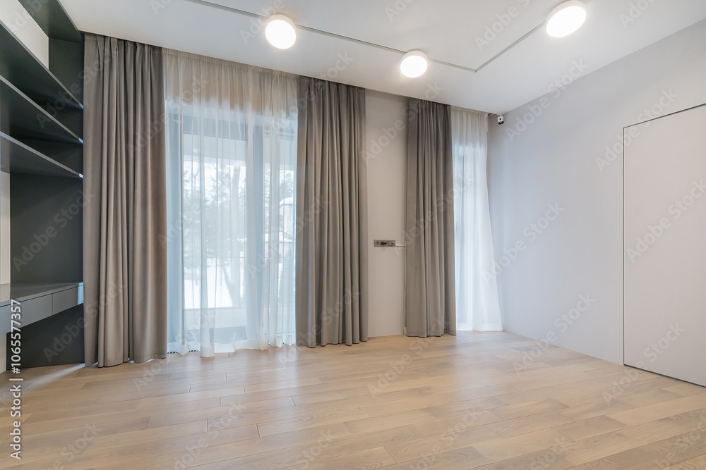 Obraz premium An empty room with a final finish. Unfurnished. Beautiful curtains on the panoramic window. Built-in shelving.