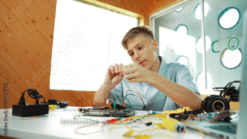 Smart happy boy inspect or learning to use electronic tool to fix car model. Highschool student studying about electric equipment to repair robotic machines while sitting at STEM class. Edification. photo