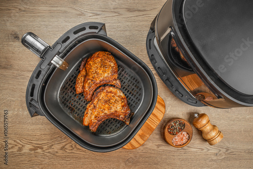 Two grilled steaks from air fryer oven on a wooden background, easy crispy food with little or no fat by circulating hot air inside the basket