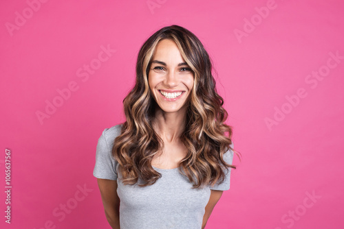 Portrait of a beautiful smiling woman with luxurious hair, positive emotions, human face on a pink background.