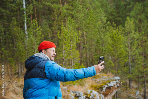 A cheerful and joyful person captures a selfie in a beautiful scenic forest landscape, surrounded by vibrant greenery and natures splendor photo