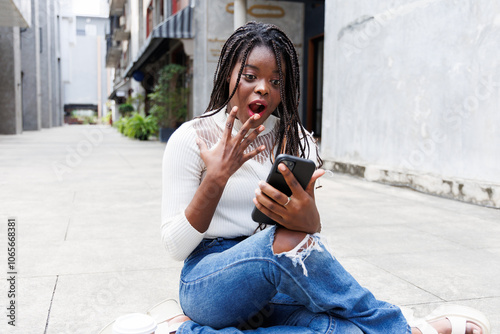 African girl excited receiving good news from watching on mobile phone
