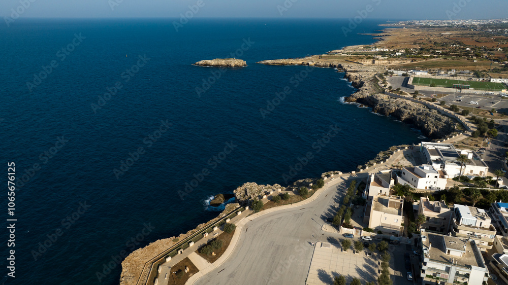 Obraz premium Aerial view of the seafront of Polignano a Mare, in the province of Bari, Puglia, Italy. There are many houses and buildings overlooking the sea.