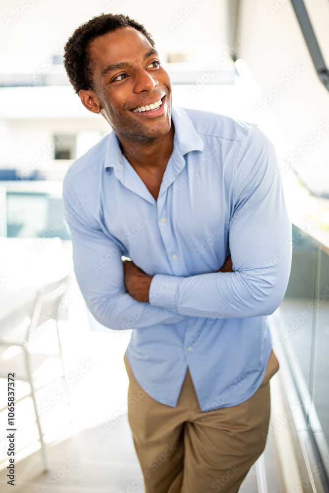 Happy man in blue shirt with arms crossed in bright modern space Happy man in blue shirt with arms crossed in bright modern space