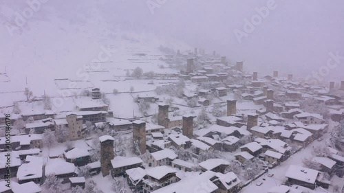 Aerial drone view video of Georgian mountain town Mestia capital of Svaneti. Snow falling in clouds, winter day in mountains