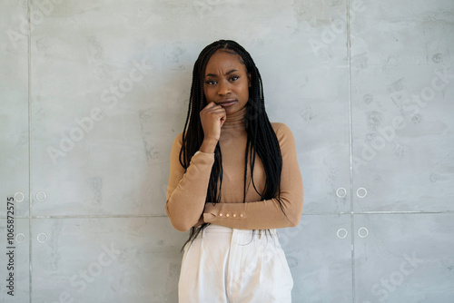 A professional Black businesswoman stands thoughtfully in a modern office, dressed smartly in business attire, exuding confidence and poise amid sleek surroundings. photo