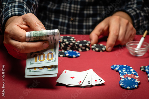 A gambler bets money on a winning combination of cards four of a kind or quads in a club. A successful poker game with a good win on a red table