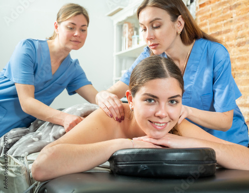 Portrait of a contented young woman lying on the procedure of a relaxing four handed massage in a spa salon. Close-up portrait.. photo