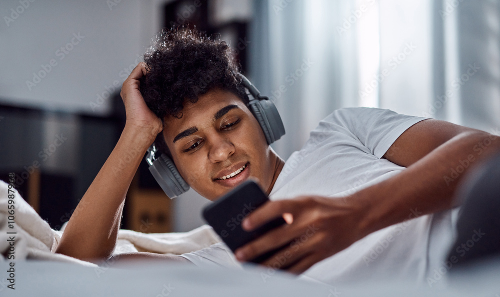 Fototapeta premium Man, headphones and browse on smartphone with bedroom, online video app or social media notification. Gen z guy, cellphone and bed with internet search, music and meme on mobile download at home