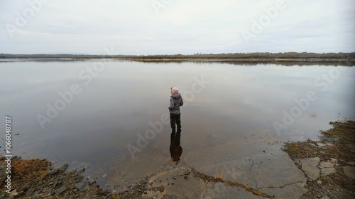 Obraz na płótnie Hiker girl standing on the rock reflected in lake at Coole park nature reserve, County Galway, Ireland, nature background w salonie