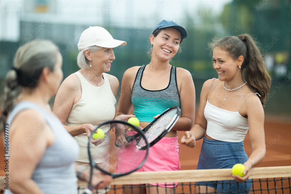 Fototapeta premium Group of young and elderly women chatting on tennis court