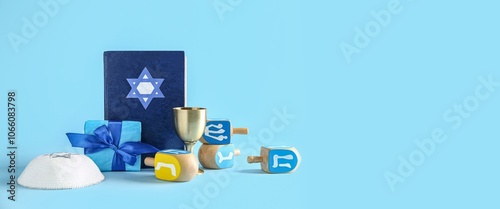 Dreidels with gift, jewish hat and Torah on blue background with space for text. Hanukkah celebration photo