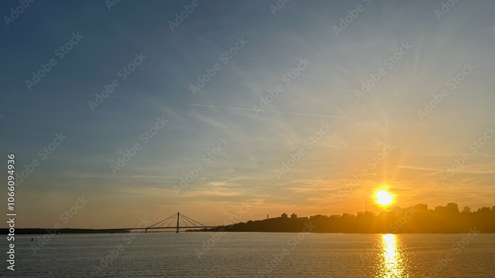 Naklejka premium Sunset over the river with a cable bridge in summer