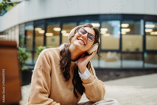 Young caucasian woman listening to music or audiobook outdoors	
 photo