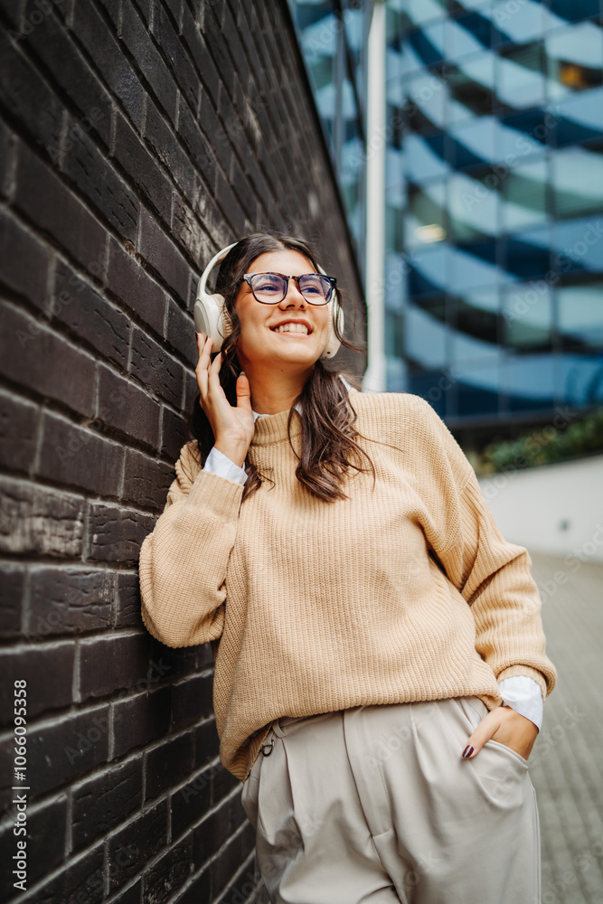 Fototapeta premium Young caucasian woman listening to music or audiobook outdoors 