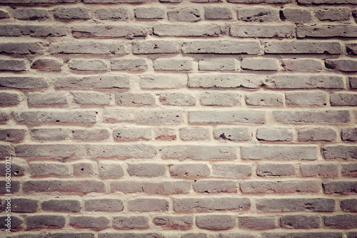 A brick wall with a few small square cutouts, showcasing the rough texture of the bricks.