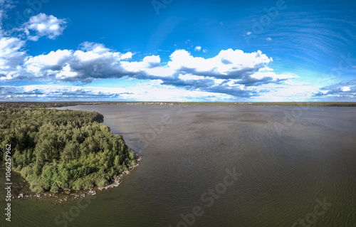 Big lake with green shores in bright sun light and city on horizon, aerial landscape. Recreation concept. Aerial view photo