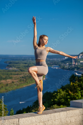 Fitness portrait young athletic woman doing gymnastics on blue sky background