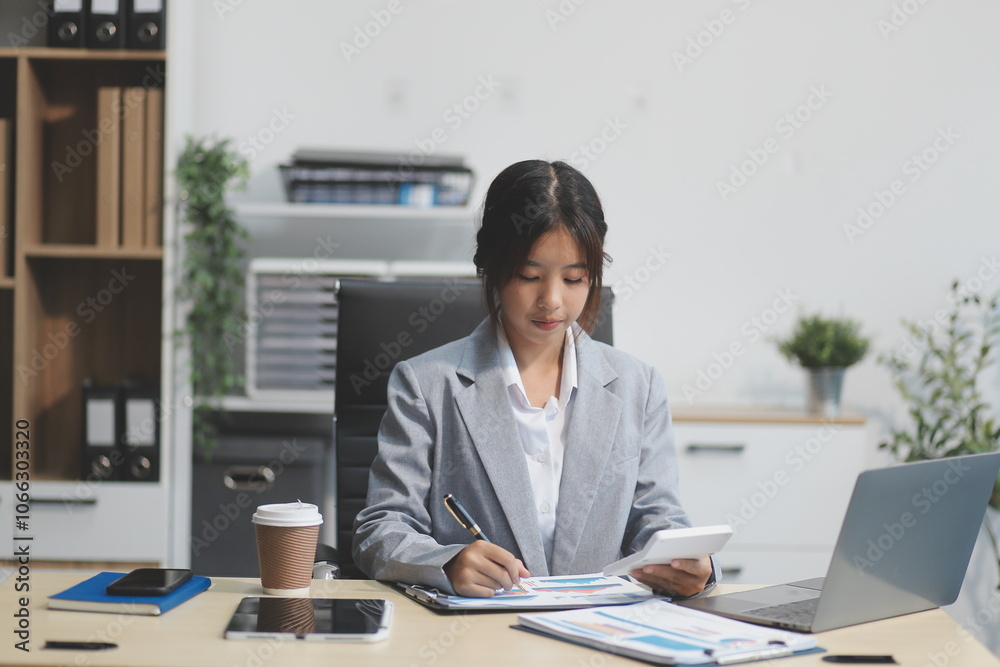 Successful Asian businesswoman smiling using laptop computer and holding coffee cup at office. Confident Asia businesswoman sitting happily in the office. Successful Asian businesswoman smiling using laptop computer and holding coffee cup at office. Confident Asia businesswoman sitting happily in the office.