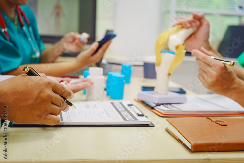 Three doctors sit together at a hospital desk, discussing bone health topics like osteoarthritis, osteoporosis, joint degeneration, ligament function, essential for skeletal structure and movement