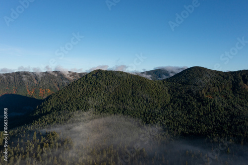 Beautiful aerial drone landscape with clouds over evergreen forests and mountains, captured early morning right after sunrise, in Mount Hood-Lost Lake territory, Oregon