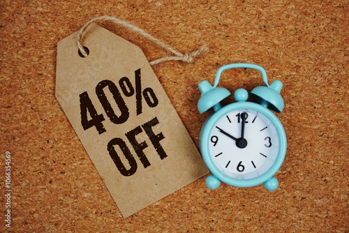 Sale 40% Off text on price tag with alarm clock on cork board background photo