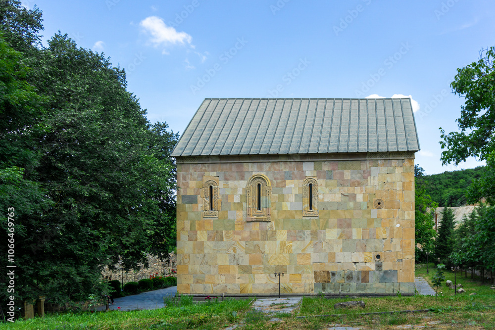 Obraz premium Church of the Holy Trinity near the town of Kazreti. Light stone walls, a beautiful garden with trees and flowers