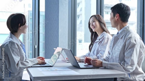 パソコンを使い会議をする作業着を着た男女