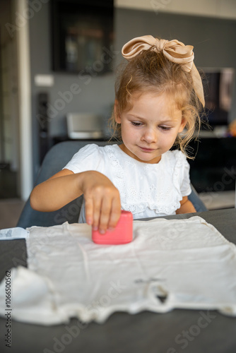 Little girl with a stamp with a name for signing children's things. Identification of personal clothing.  photo