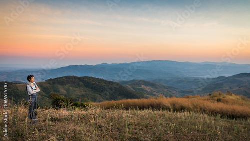 Woman traveler looking at the sunset over mountain view at Doi Chang , Chiangrai, Thailand