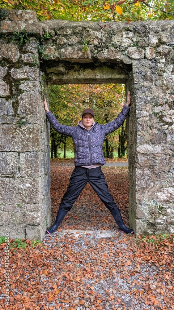 Portrait of pretty hiker girl at medieval stone entrance at Coole park nature reserve at county Galway, Ireland, people background