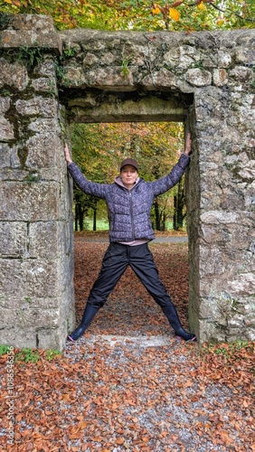 Obraz na płótnie Portrait of pretty hiker girl at medieval stone entrance at Coole park nature reserve at county Galway, Ireland, people background w salonie