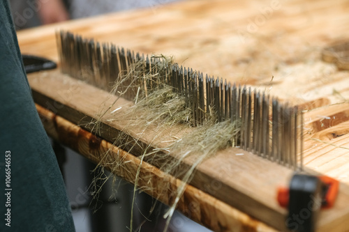 Traditional flax processing with hackling tool on wooden table for craft and textile design