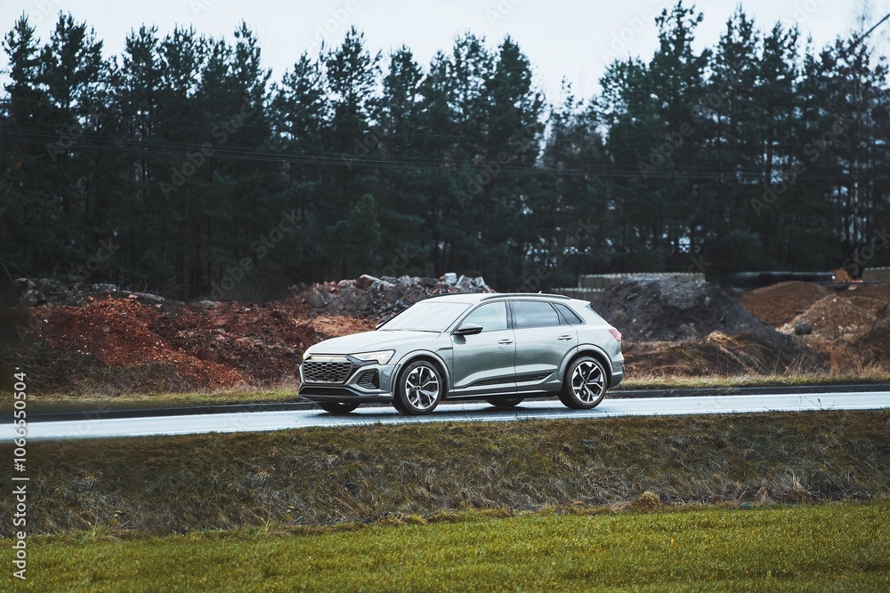 SUV on rainy countryside drive with green and dirt hills SUV on rainy countryside drive with green and dirt hills